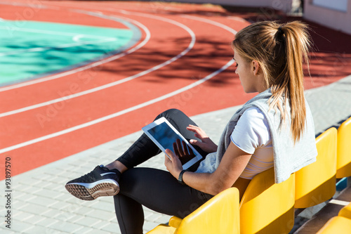Fototapeta Naklejka Na Ścianę i Meble -  Woman resting with tablet computer at stadium