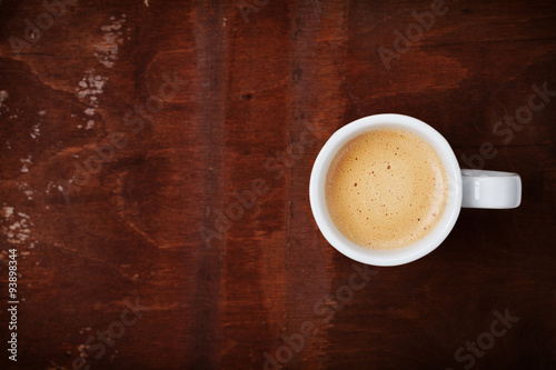 Full cup of fresh coffee on rustic wooden table, top view