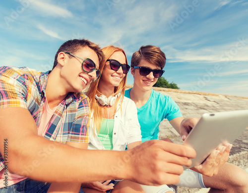 group of smiling friends with tablet pc outdoors © Syda Productions