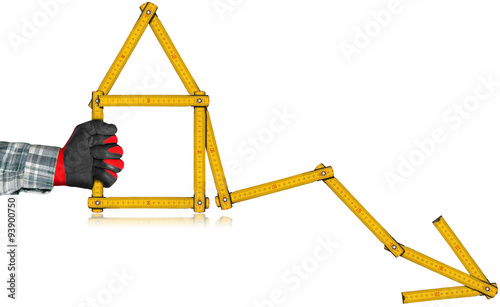 Real Estate - Decreasing Sale Graph / Hand with work glove holding a wooden yellow meter in the shape of house and diagram of decrease. Isolated on white background