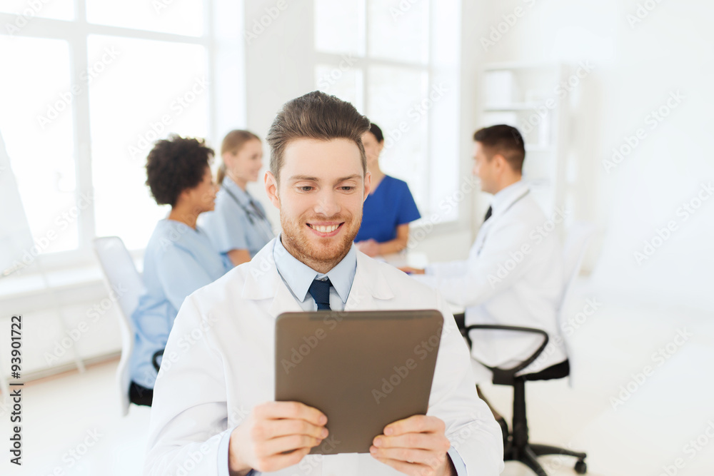 happy doctor with tablet pc over team at clinic