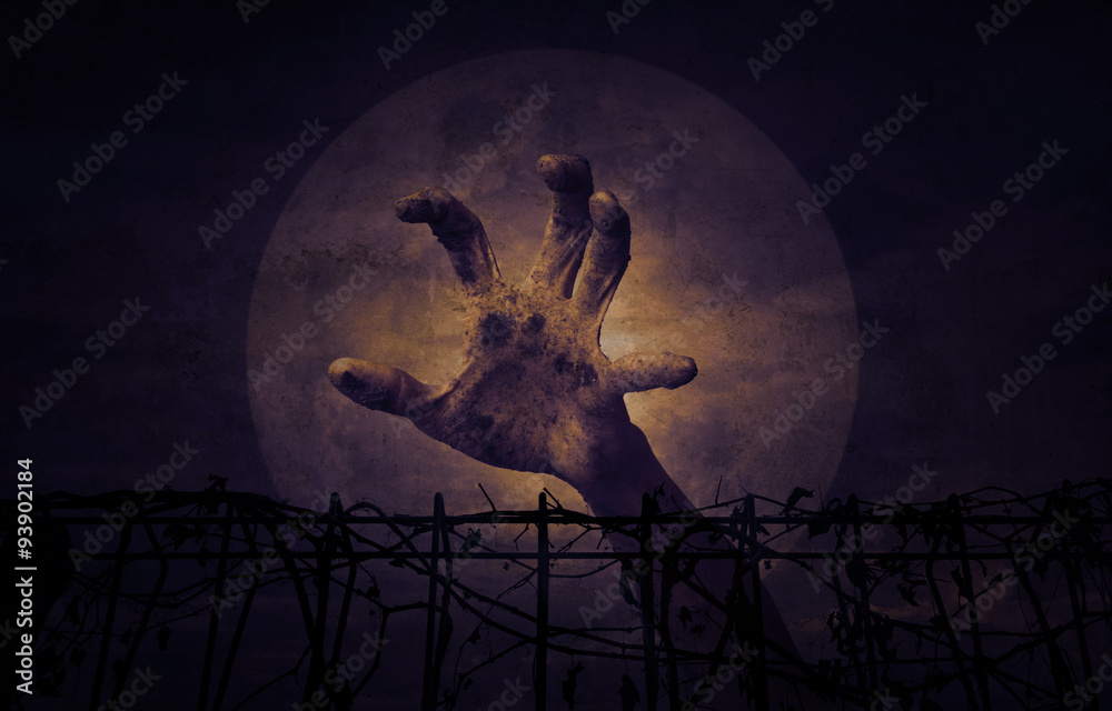 Hand over metal fence with dry leaves over dark sky, Halloween c