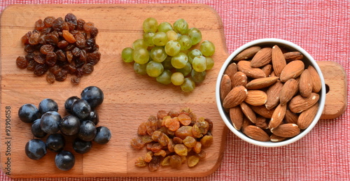 Various raisins, vine berries and almonds on chopping board