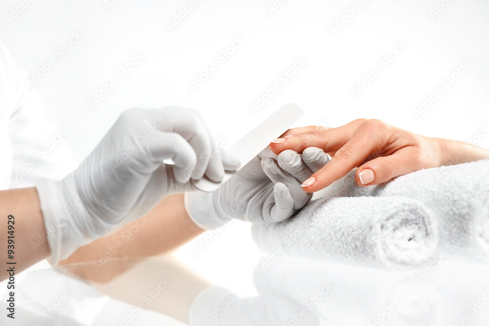 Obraz premium Piłowanie paznokci, manicure. Zabieg pielęgnacyjny dłoni i paznokci, kobieta u kosmetyczki na zabiegu manicure.