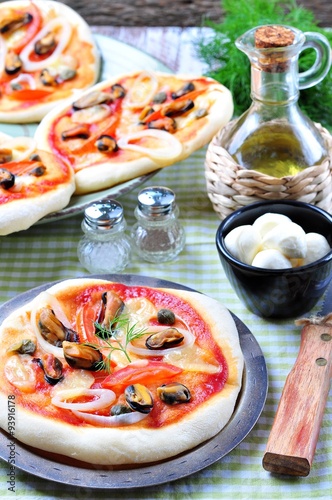 homemade mini pizza with mussels, calamari, onion, tomato, mozzarella and capers