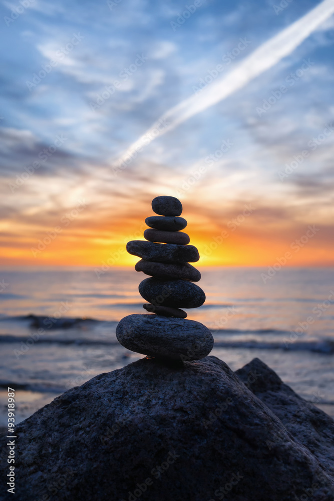 Stable vertical cairn at sunset on the sea