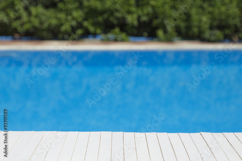 Wooden table mat with swimming pool and bushes in the background 