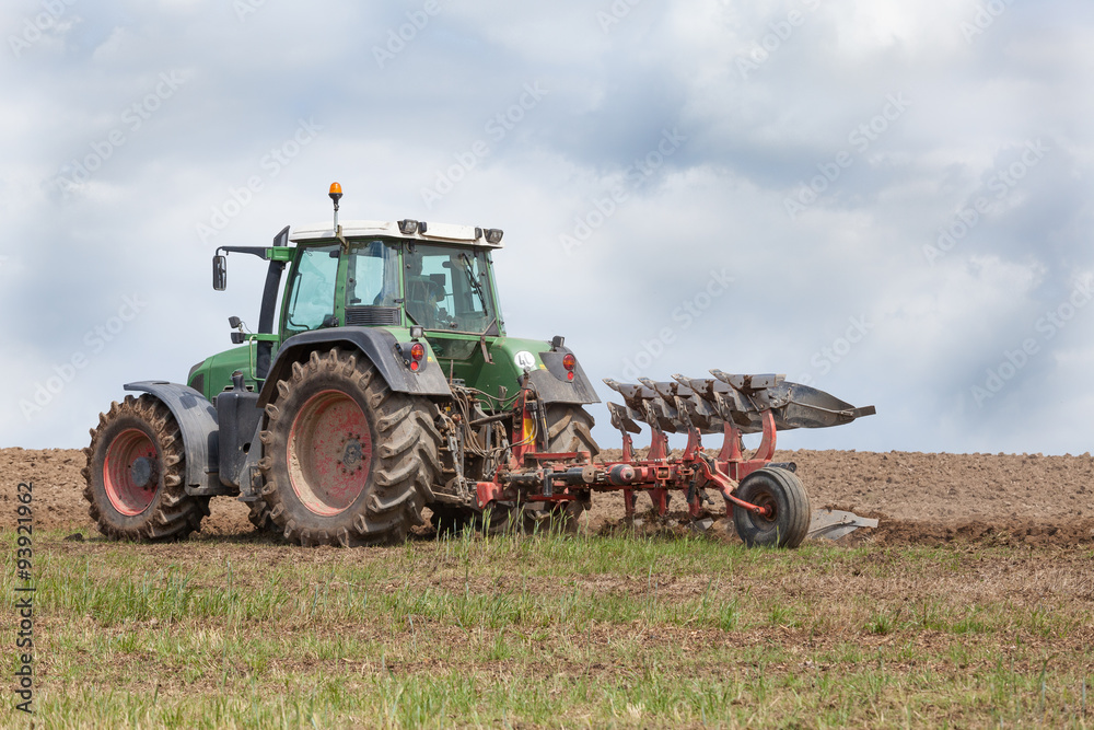 Farmer preparing a field for planting - ploughing it with an agricultural plough, close up of the tractor and implement on the skyline Farmer preparing a field for planting - ploughing it with an agricultural plough, close up of the tractor and implement on the skyline