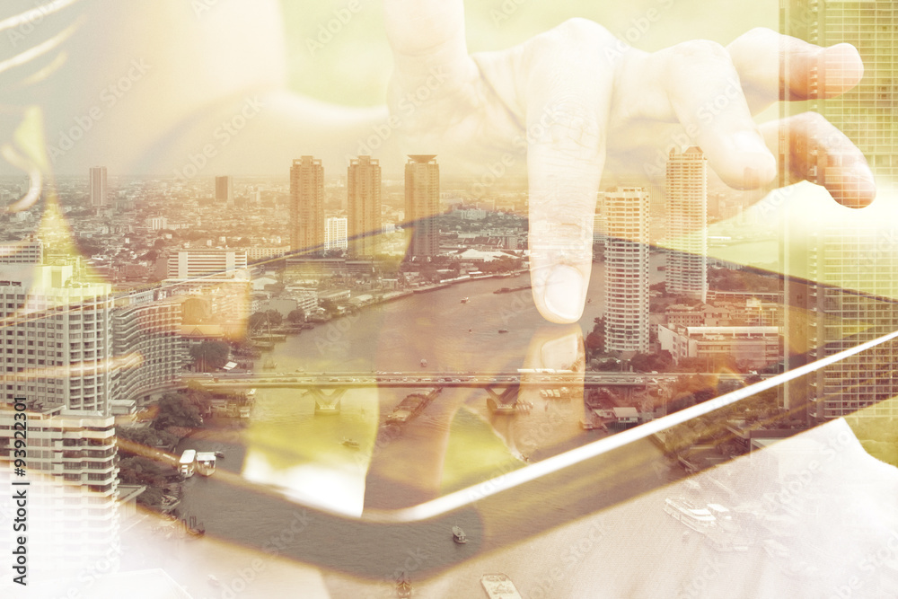Using digital tablet double exposure and and cityscape background. Business & technology concept.