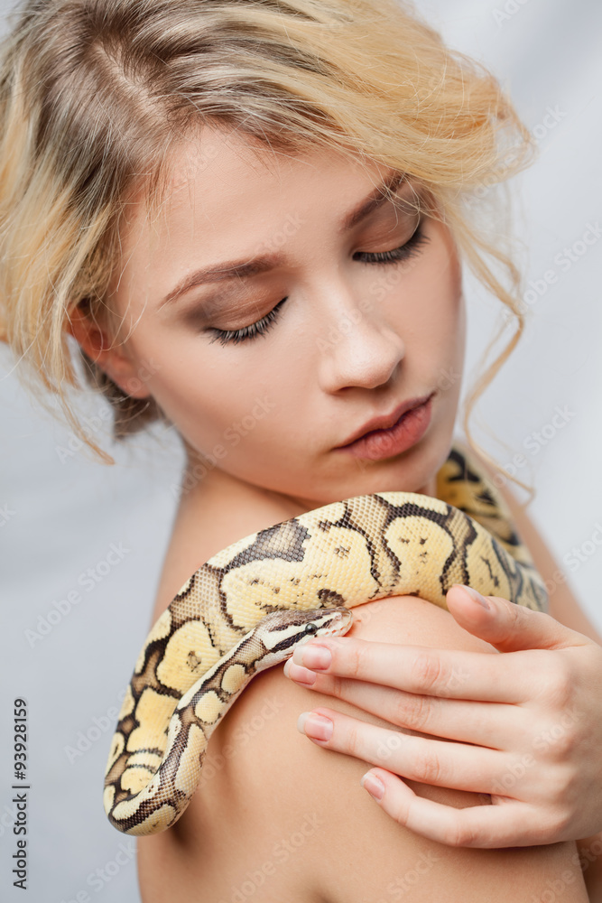 Fototapeta premium Beautiful girl holding a python, which wraps around her body