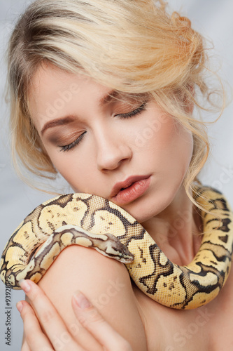 Beautiful girl holding a python, which wraps around her body