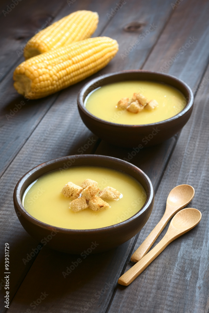 Cream of corn soup with croutons on top, photographed on dark wood with natural light (Selective Focus, Focus on the front of the croutons on the first soup) Cream of corn soup with croutons on top, photographed on dark wood with natural light (Selective Focus, Focus on the front of the croutons on the first soup)