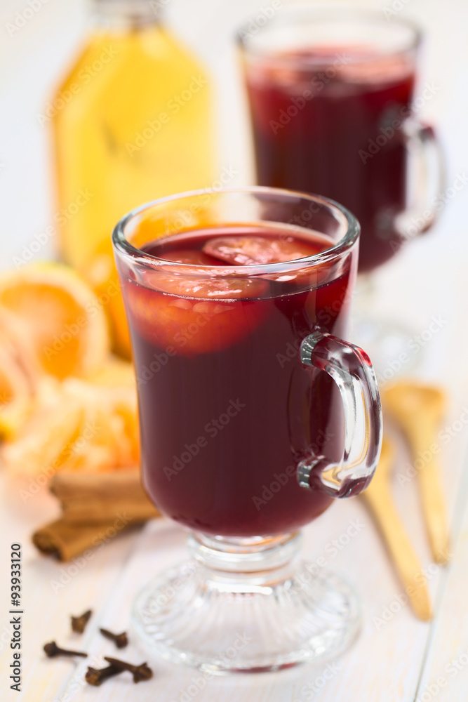 Hot spiced mulled red wine with mandarin on top (Selective Focus, Focus on the front of the rim and the handle of the glass) Hot spiced mulled red wine with mandarin on top (Selective Focus, Focus on the front of the rim and the handle of the glass)