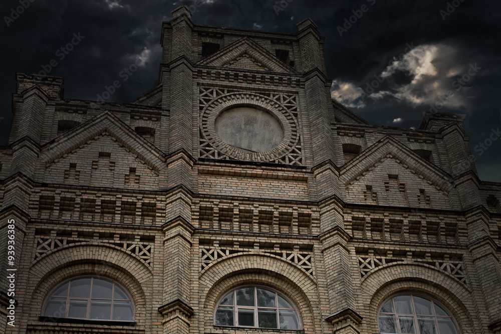 Detail of the facade of an old university building on a background of storm clouds