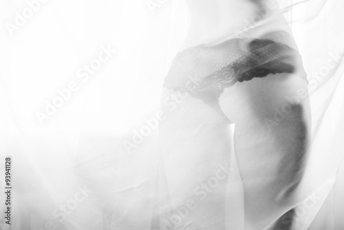Glamor sexy girl with excellent fitness buttocks having fun happy standing back to camera over window light copy space background. Closeup black and white photography