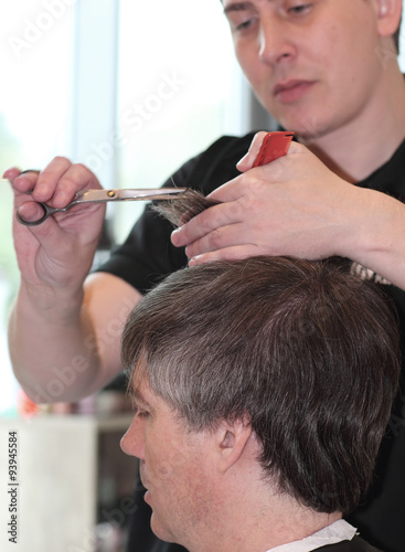 A man cuts hair in a barbershop. Master young stylist.Focus on grey hair