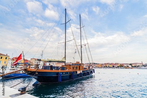 A galleass anchored among ships in the Adriatic sea with a view of the old city core buildings on the coast