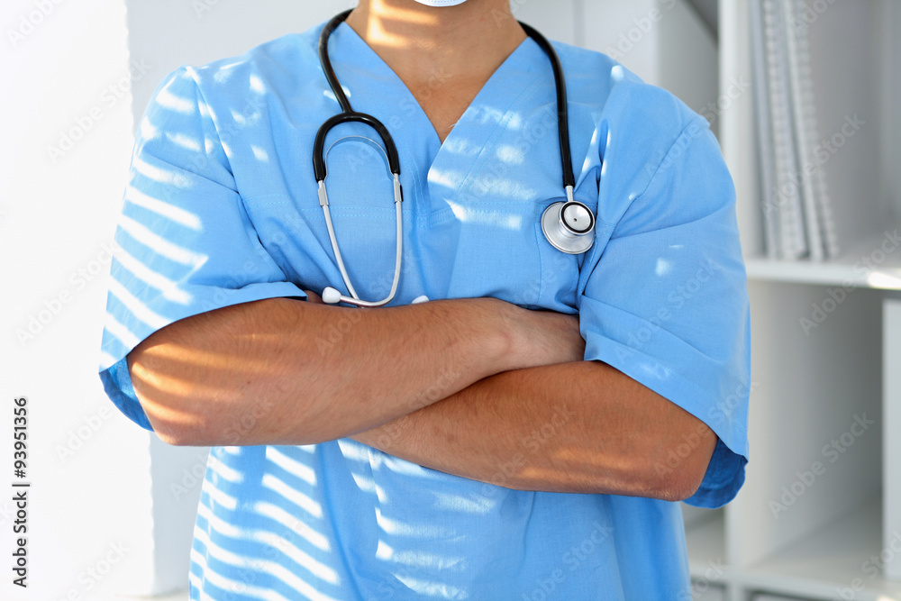 Portrait of unknown male surgeon doctor holding his stethoscope, crossed arms