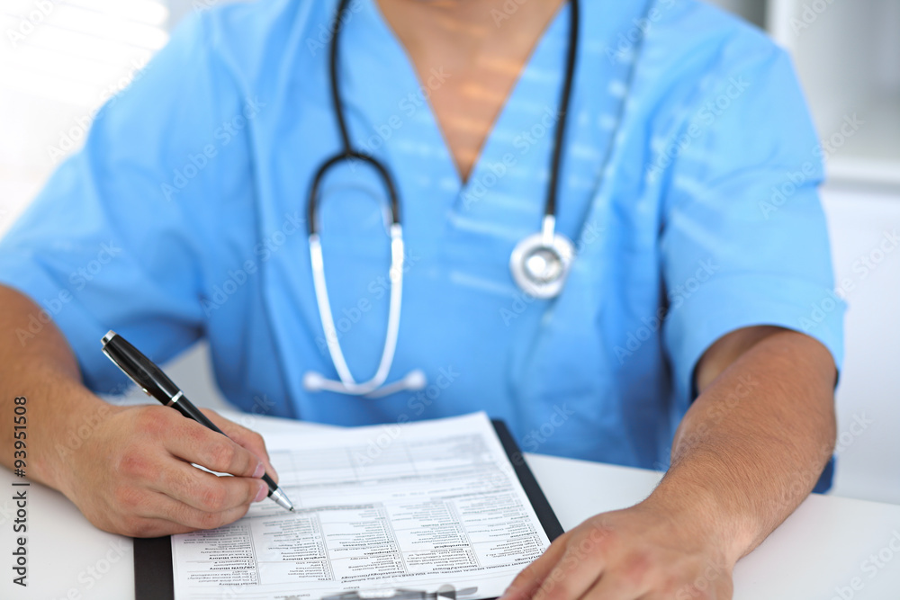 Portrait of unknown male surgeon doctor holding his stethoscope and filling up medical history Portrait of unknown male surgeon doctor holding his stethoscope and filling up medical history