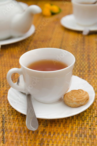 Cup of tea spoon and cookies on saucer
