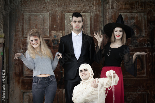 Zombie, vampire, witch and mummy standing in front of the door of the haunted house photo