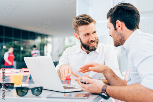 Two young modern businessman using laptop