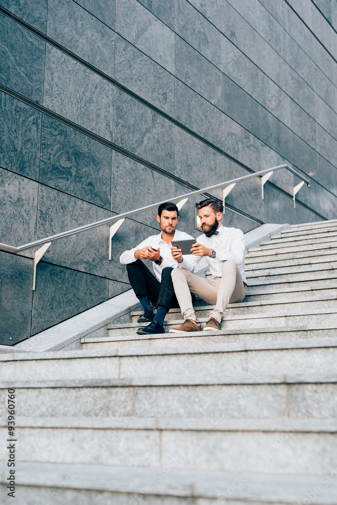 Two young modern businessman using tablet