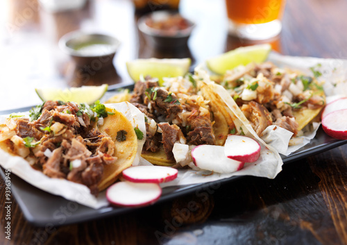 plate of authentic mexican street style tacos with radish slices