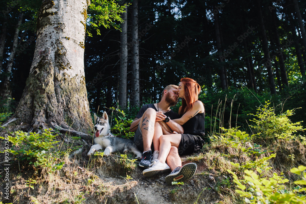 Naklejka premium beautiful couple sitting in a forest near the tree