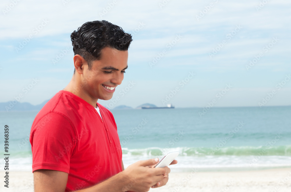 Latino im roten Shirt chattet mit dem Handy