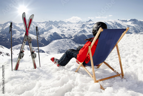 Women at mountains in winter lies on sun-lounger