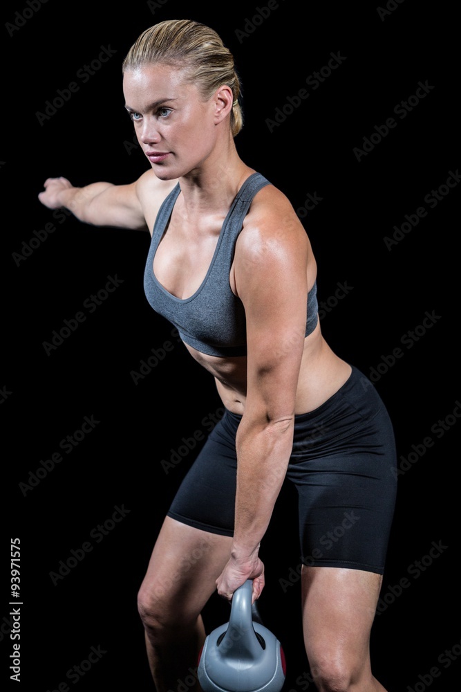 Muscular woman swinging heavy kettlebell Muscular woman swinging heavy kettlebell