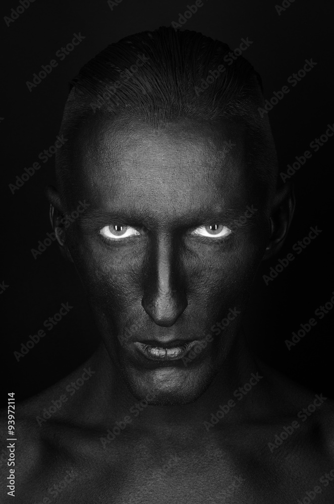 Gothic and Halloween theme: a man with black skin is isolated on a black background in the studio, the Black Death body art Gothic and Halloween theme: a man with black skin is isolated on a black background in the studio, the Black Death body art