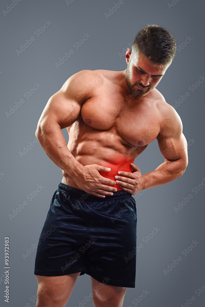 Bodybuilder with pain in left side of belly. Strong man having pancreas pain and holding hands on abdomen. Red highlighted zone.