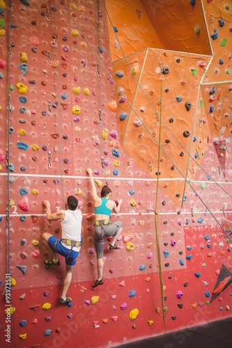 Couple climbing up rock wall