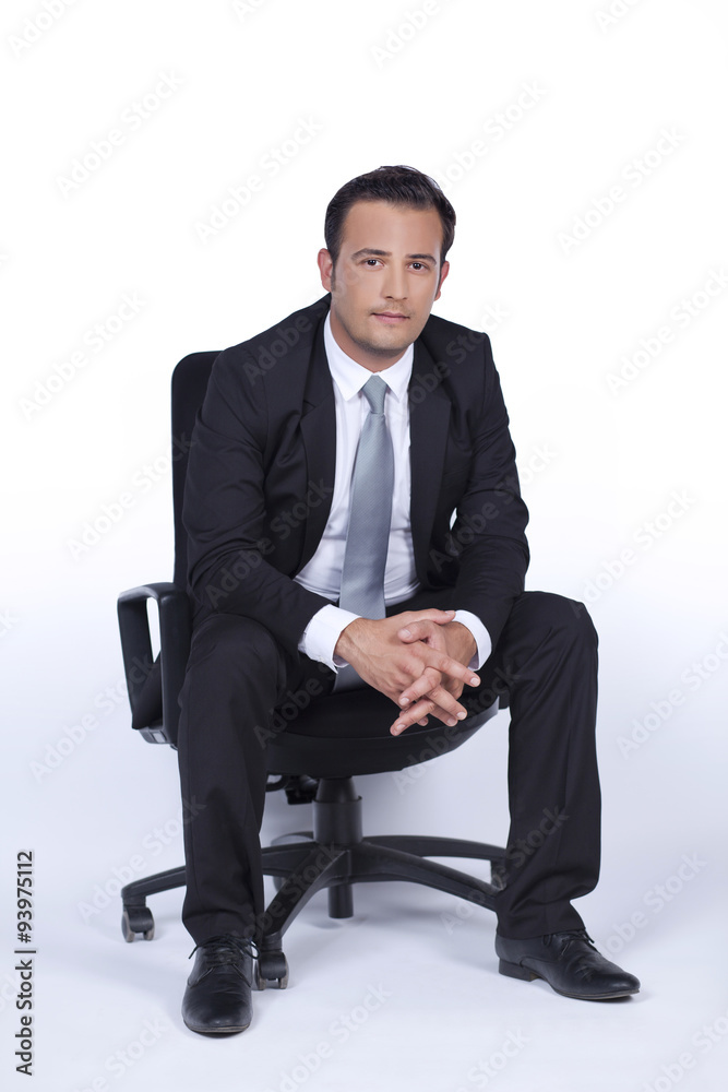 Handsome businessman is sitting on a chair and looking us Handsome businessman is sitting on a chair and looking us