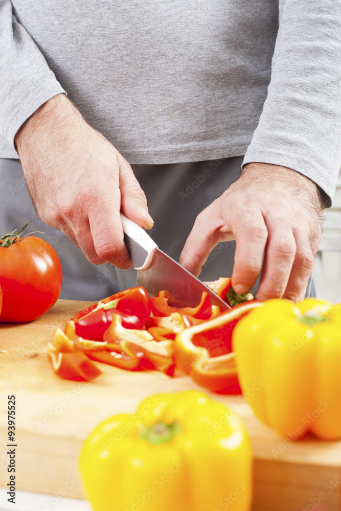 Close up of male hands cutting red pepper on cutting board at home Close up of male hands cutting red pepper on cutting board at home