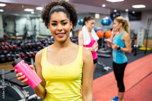 Fit woman smiling at camera in weights room