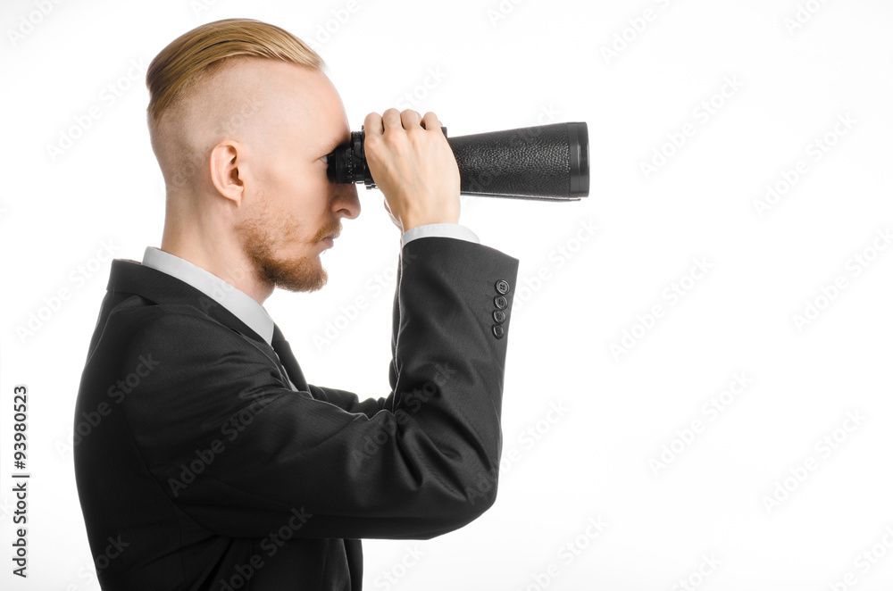Fototapeta premium Business and search topic: Man in black suit holding a black binoculars in hand on white isolated background in studio