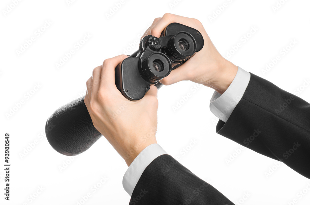 Business and search topic: Man in black suit holding a black binoculars in hand on white isolated background in studio Business and search topic: Man in black suit holding a black binoculars in hand on white isolated background in studio