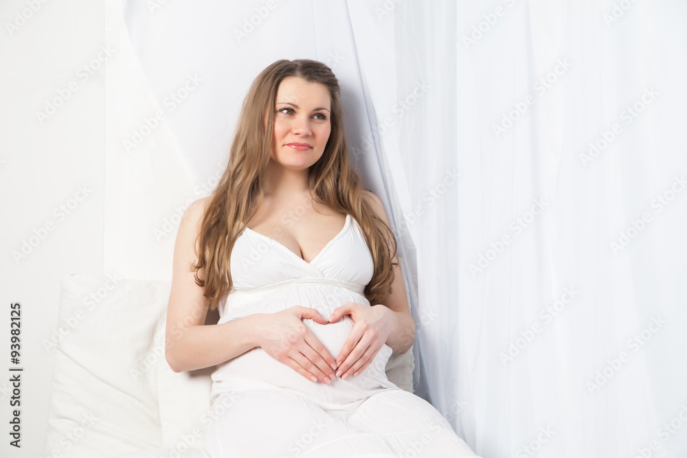 beautiful pregnant woman in white dress near window beautiful pregnant woman in white dress near window