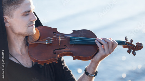 Foto Violinist playing a violin,  young man plays on the background