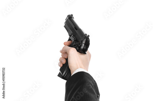Firearms and security topic: a man in a black suit holding a gun on an isolated white background in studio
