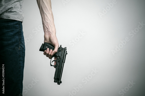 Horror and firearms topic: suicide with a gun on a gray background in the studio