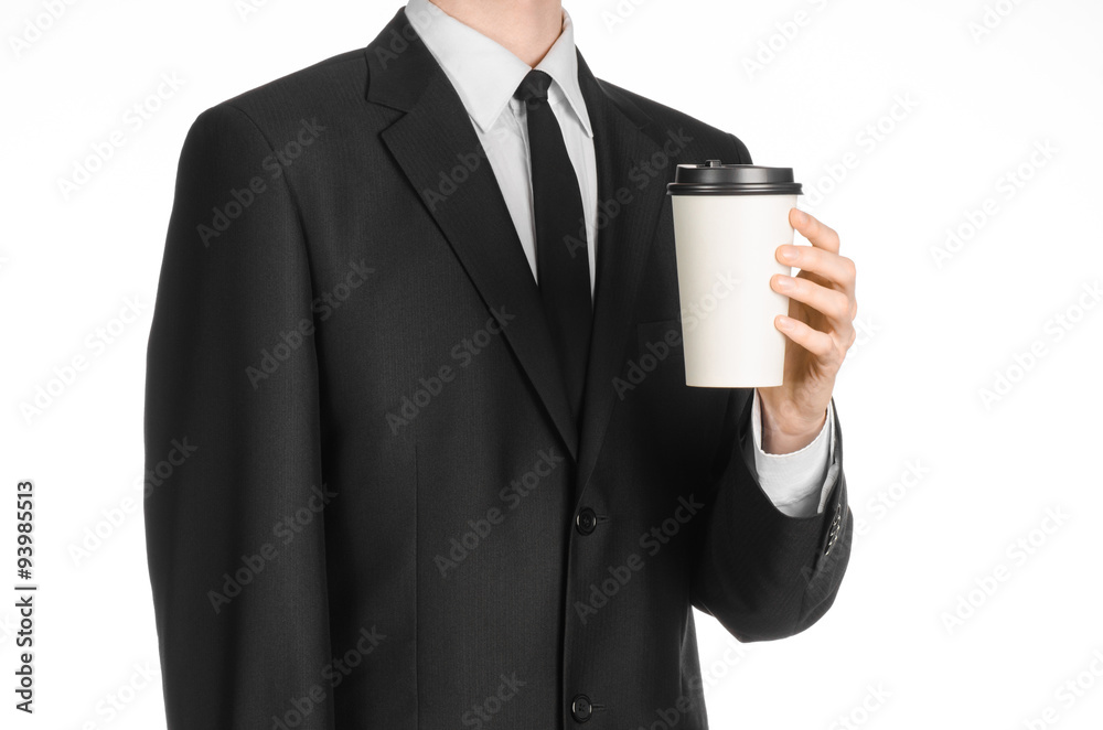 Business lunches coffee theme: businessman in a black suit holding a white blank paper cup of coffee with a brown plastic cap isolated on a white background in the studio, advertising coffee Business lunches coffee theme: businessman in a black suit holding a white blank paper cup of coffee with a brown plastic cap isolated on a white background in the studio, advertising coffee