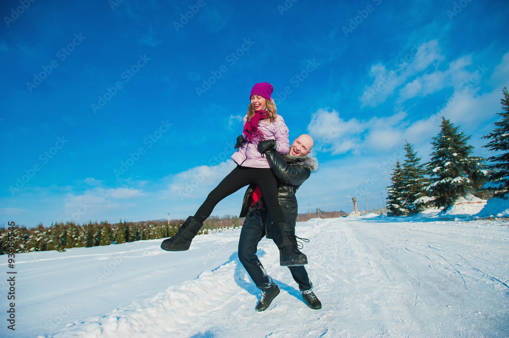 Young beautiful couple in bright clothes winter fun in the snow, lifestyle, winter holidays