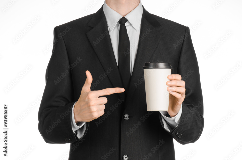 Business lunches coffee theme: businessman in a black suit holding a white blank paper cup of coffee with a brown plastic cap isolated on a white background in the studio, advertising coffee Business lunches coffee theme: businessman in a black suit holding a white blank paper cup of coffee with a brown plastic cap isolated on a white background in the studio, advertising coffee