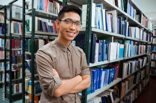 Man standing with arms folded in university library
