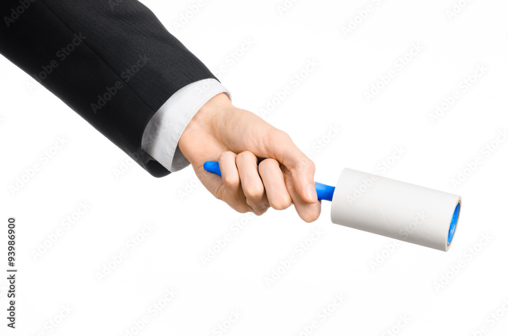 Dry cleaning and business theme: a man in a black suit holding a blue sticky brush for cleaning clothes and furniture from dust isolated on white background in studio. Dry cleaning and business theme: a man in a black suit holding a blue sticky brush for cleaning clothes and furniture from dust isolated on white background in studio.