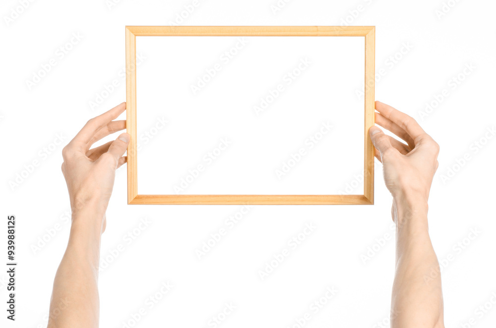 House decoration and Photo Frame topic: human hand holding a wooden picture frame isolated on a white background in the studio first-person view House decoration and Photo Frame topic: human hand holding a wooden picture frame isolated on a white background in the studio first-person view